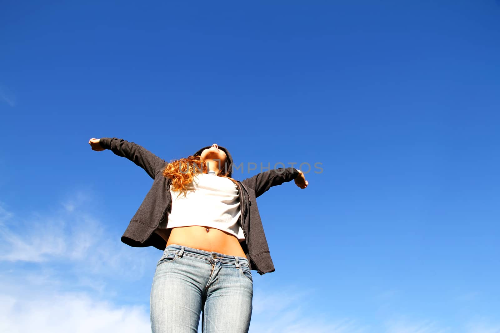 A young woman standing under a blue sky.