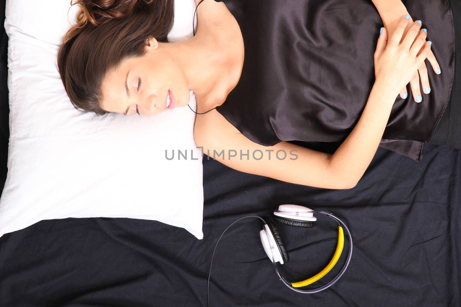 A young girl sleeping in bed with headset.  
