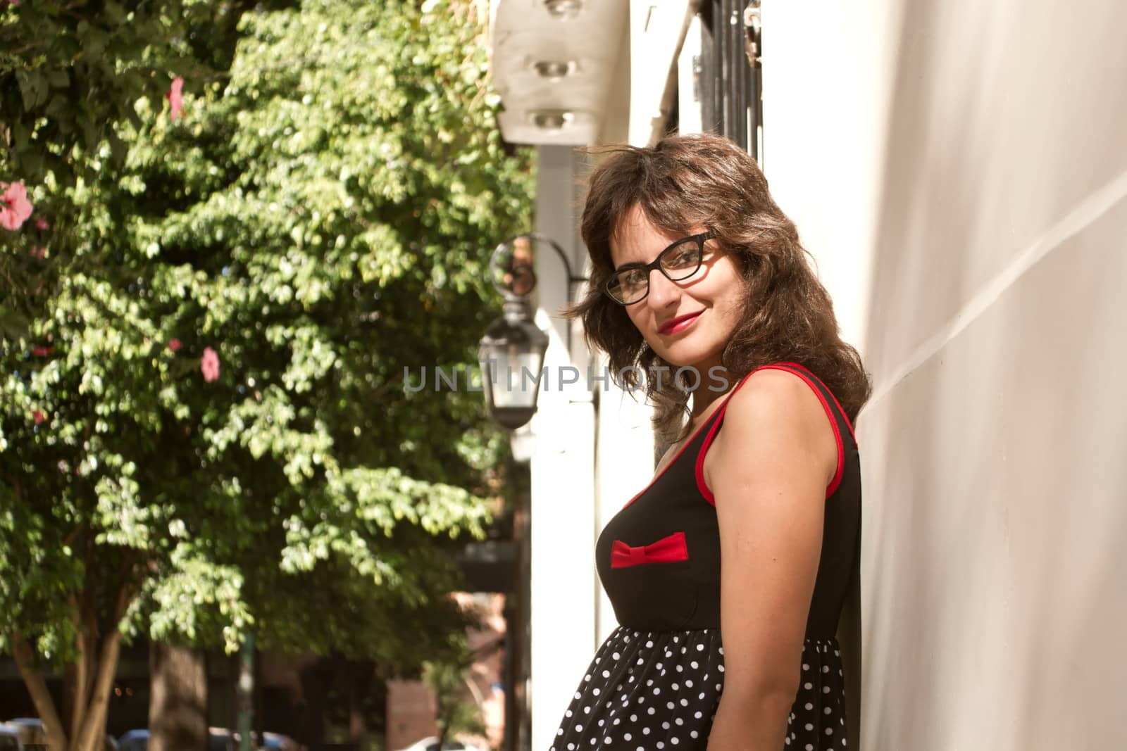 A vintage style dressed girl leaning at a wall and waiting.