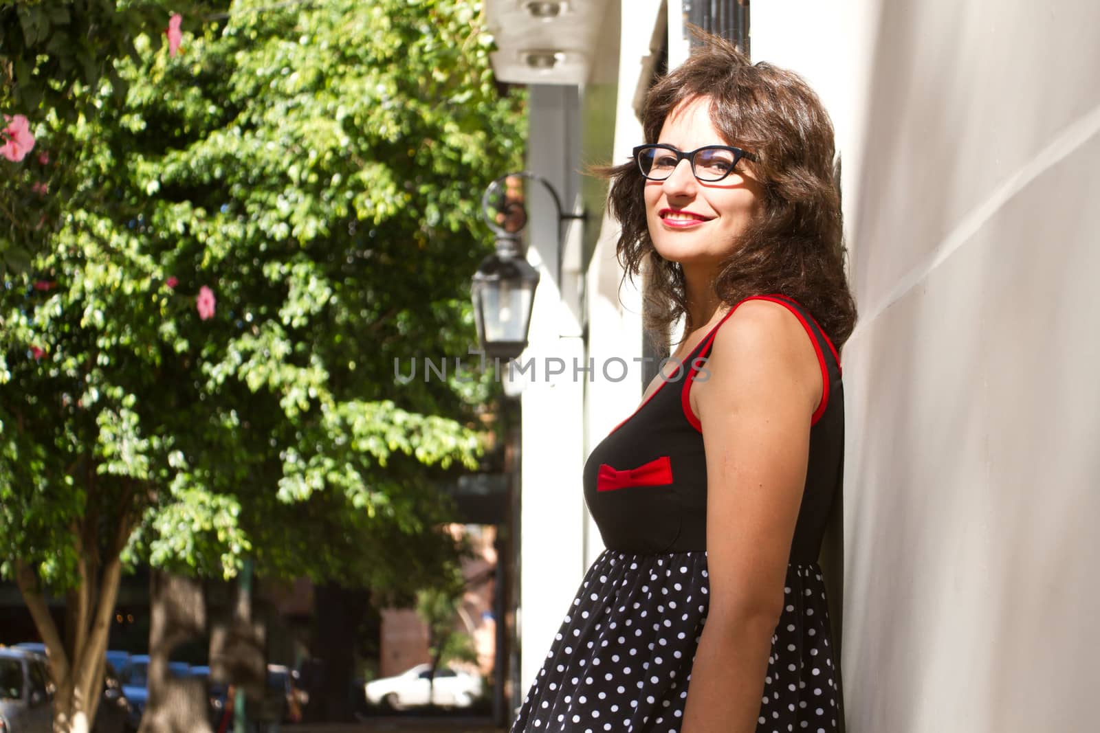 A vintage style dressed girl leaning at a wall and waiting.