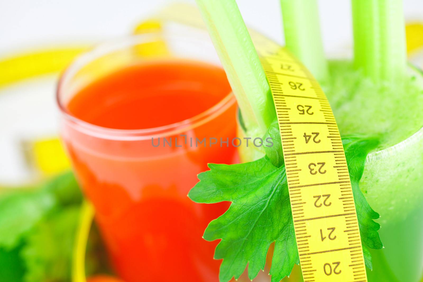 measuring tape, glass of celery juice and glass of carrot juice isolated on white