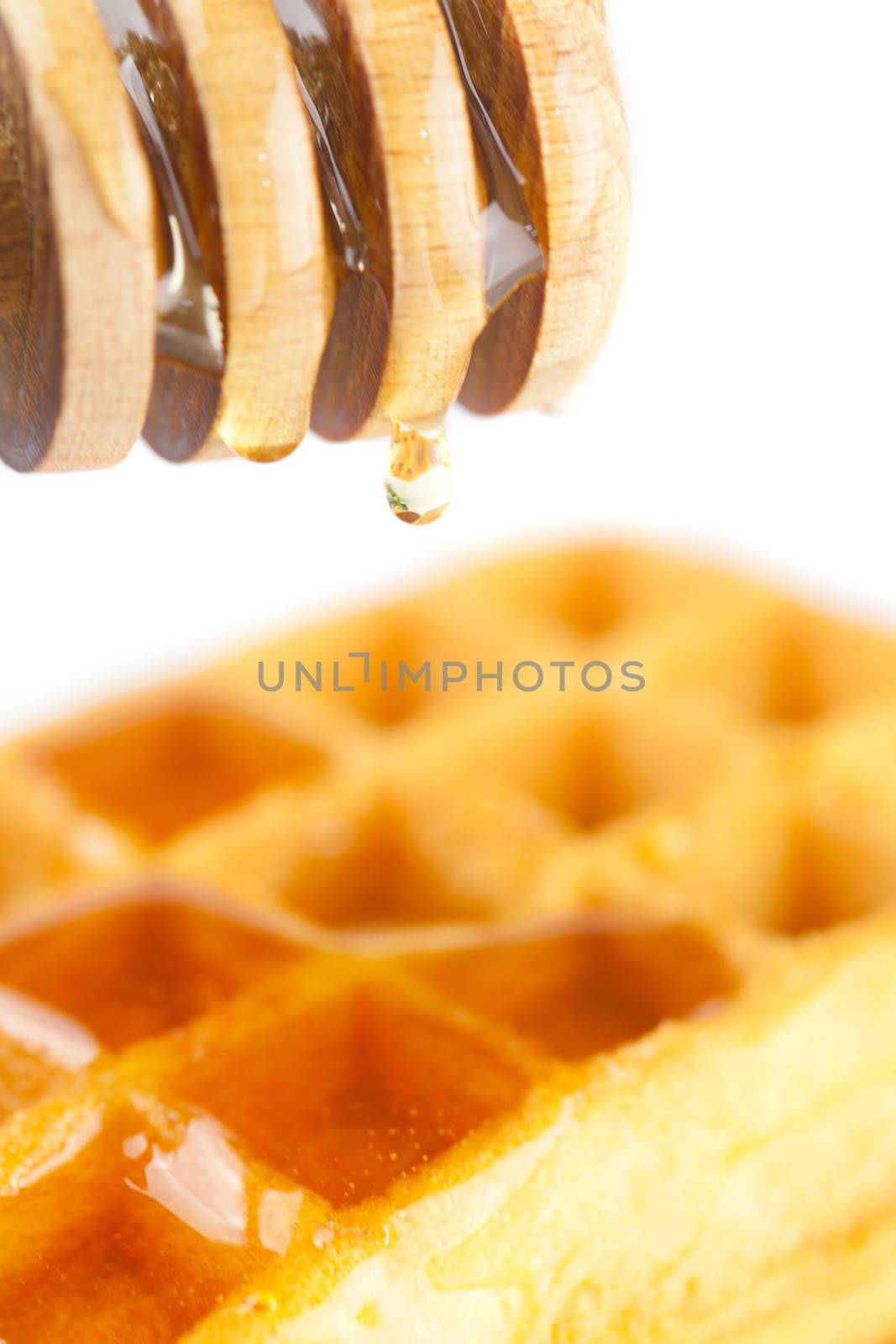 Belgian waffles on a plate, stick for honey and honey isolated on white