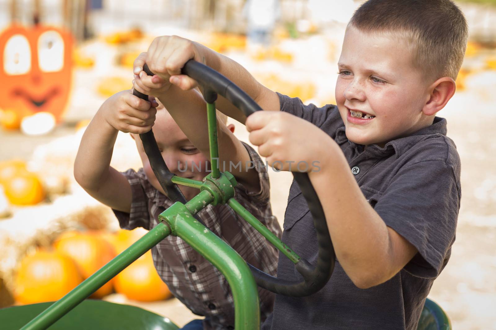 Adorable Young Boys Playing on an Old Tractor in a Rustic Outdoor Fall Setting.
