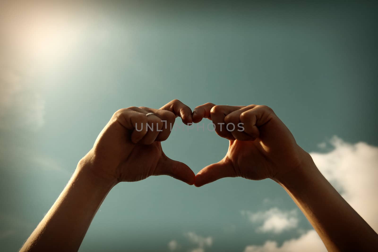 Toned Photo of Hands in Heart Shape on Sky Background