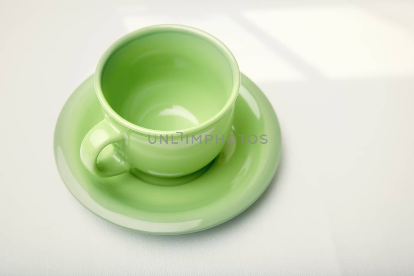 Green teacup on a table with shadow