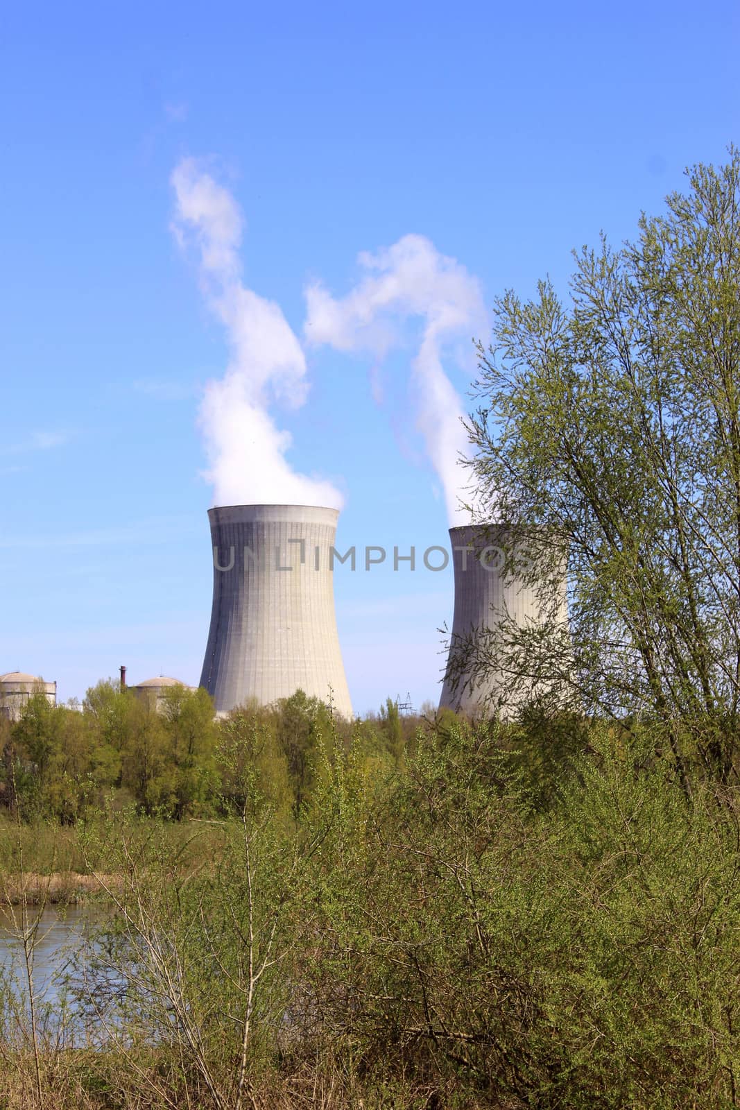 photo of an operating nuclear power plant on the banks of a river surrounded by trees