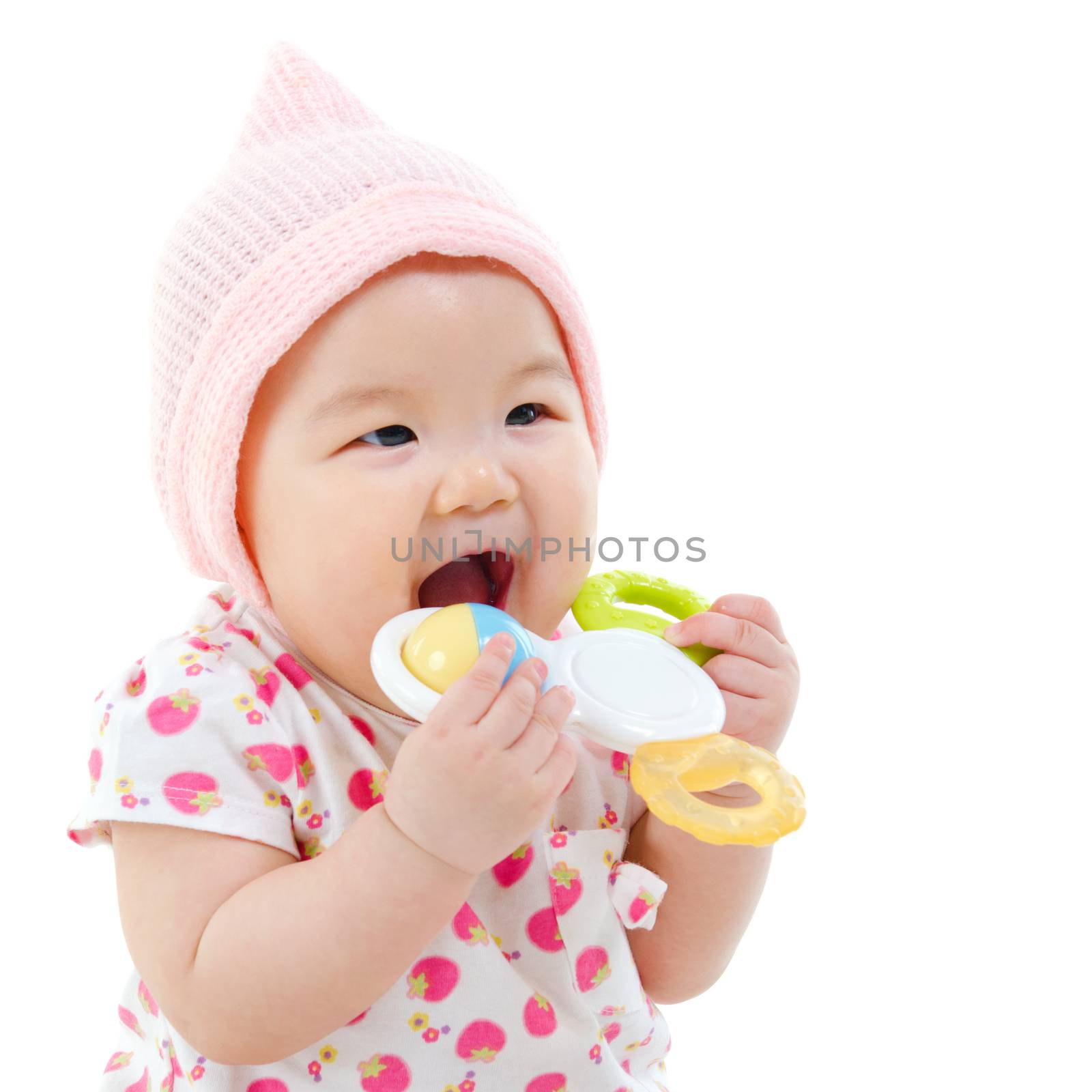 Beautiful mixed race Asian baby girl teething, biting with her toys, isolated on white background.