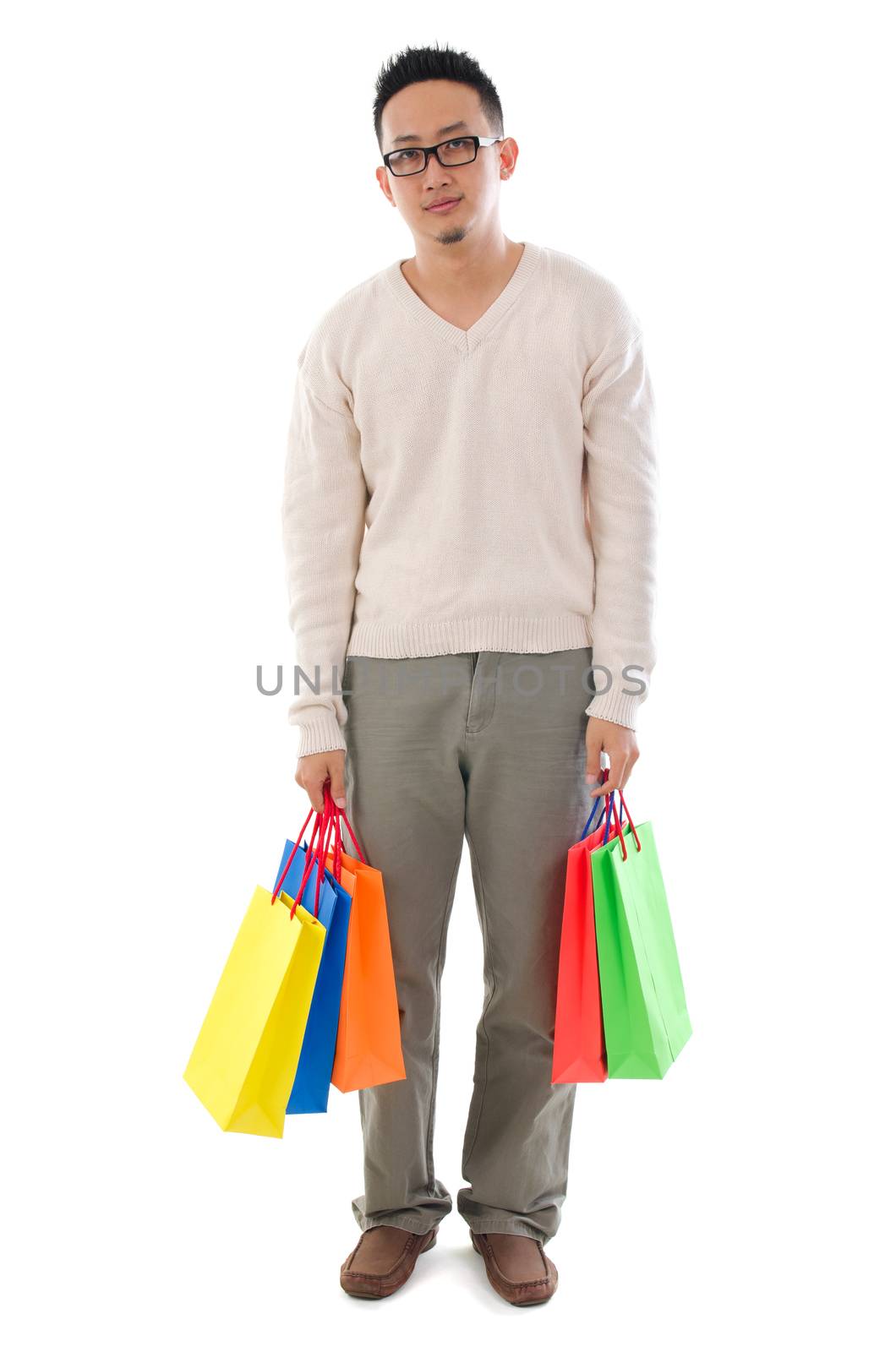 Bored Asian man shopper holding shopping bags waiting for his girlfriend standing isolated over white background