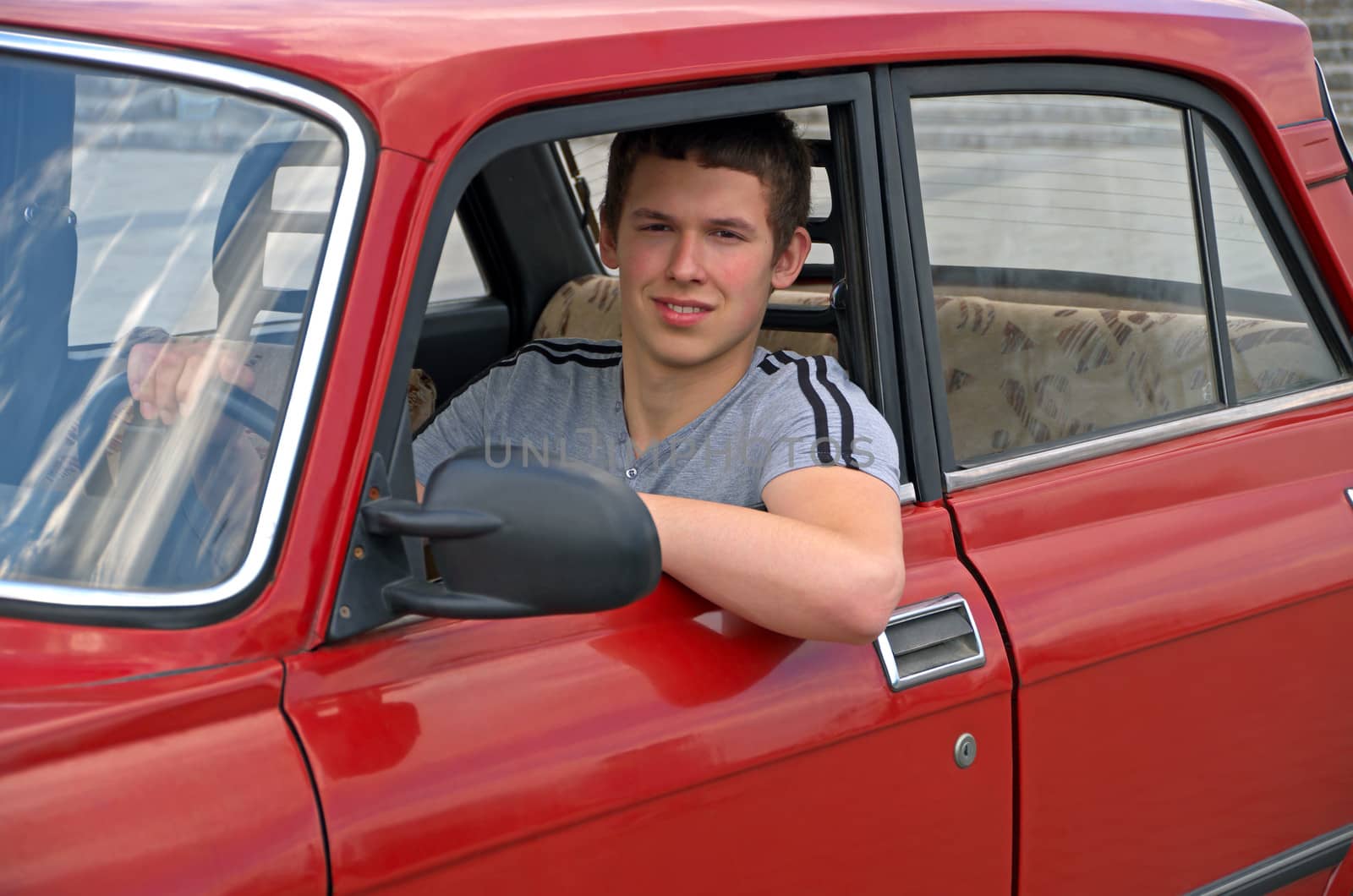 The young man behind the wheel of an old auto 70-80 years of release.