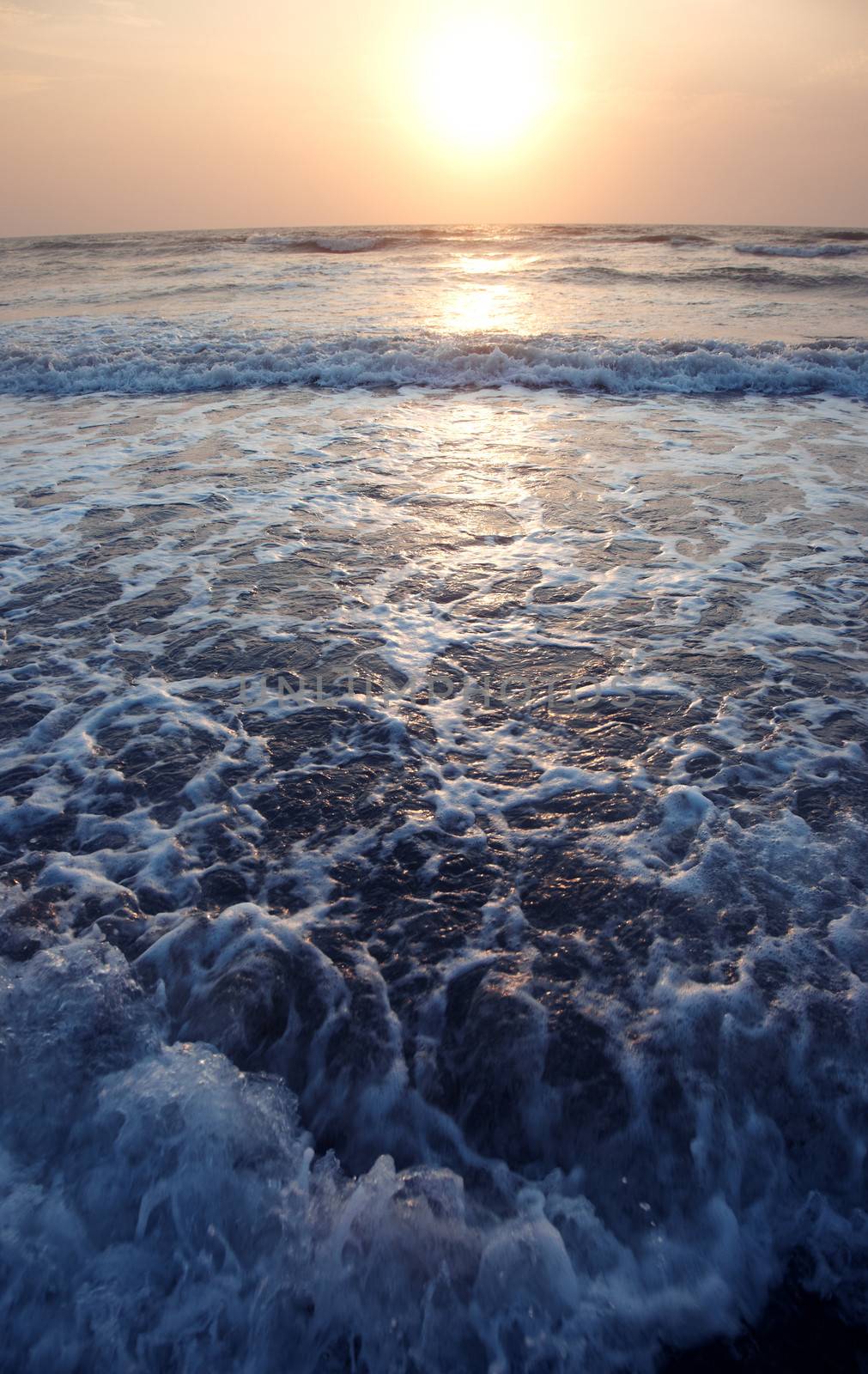 Seaside with waves during sunset. Vertical photo