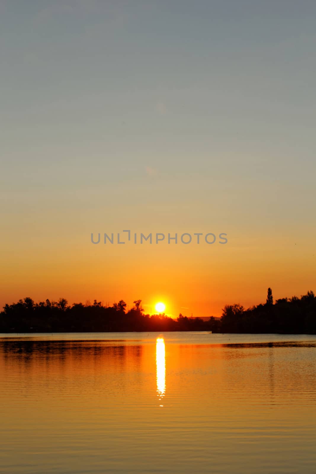 Colorful sunset over tranquil water surface.