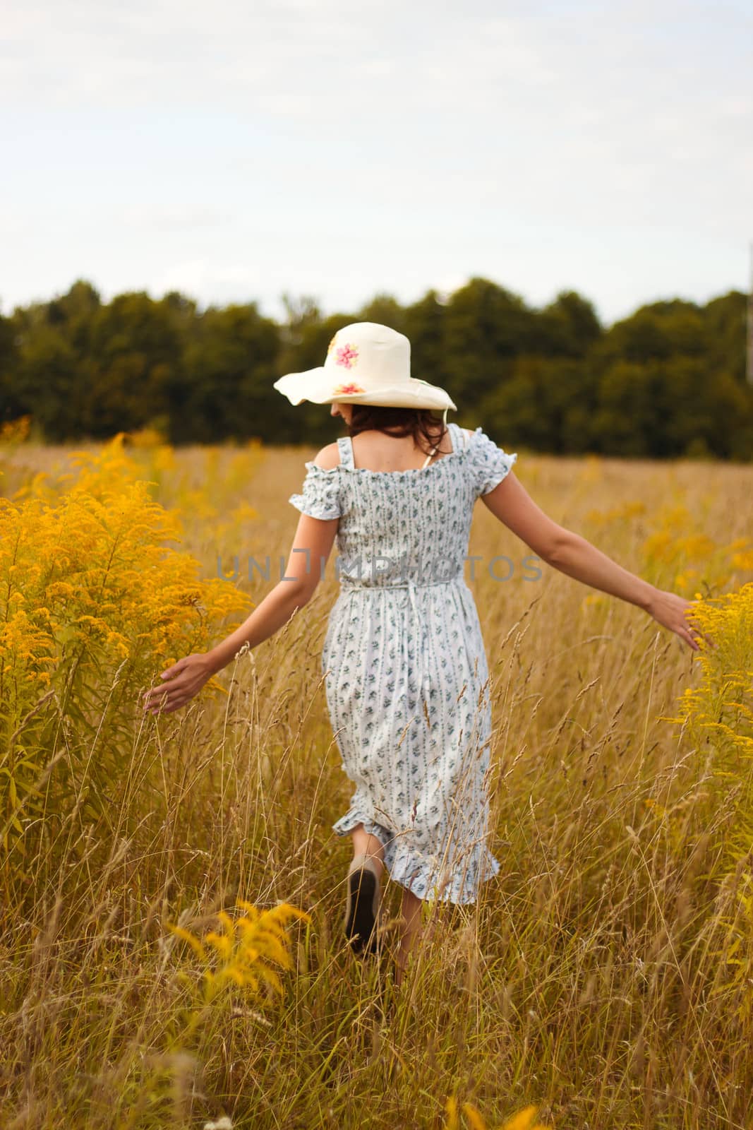 Portrait of beautiful young woman with flowers in the field
