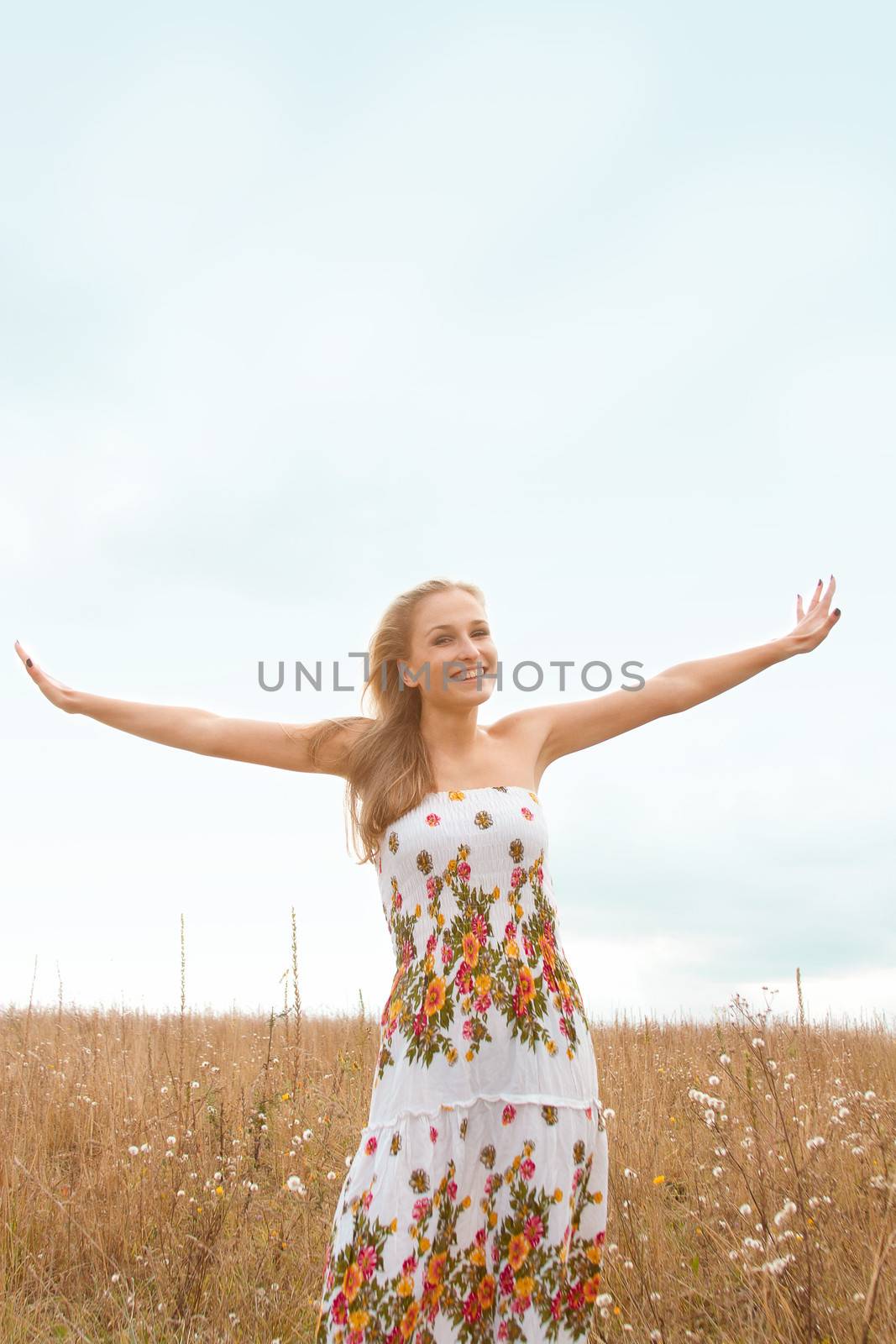 Portrait of beautiful young woman with flowers in the field