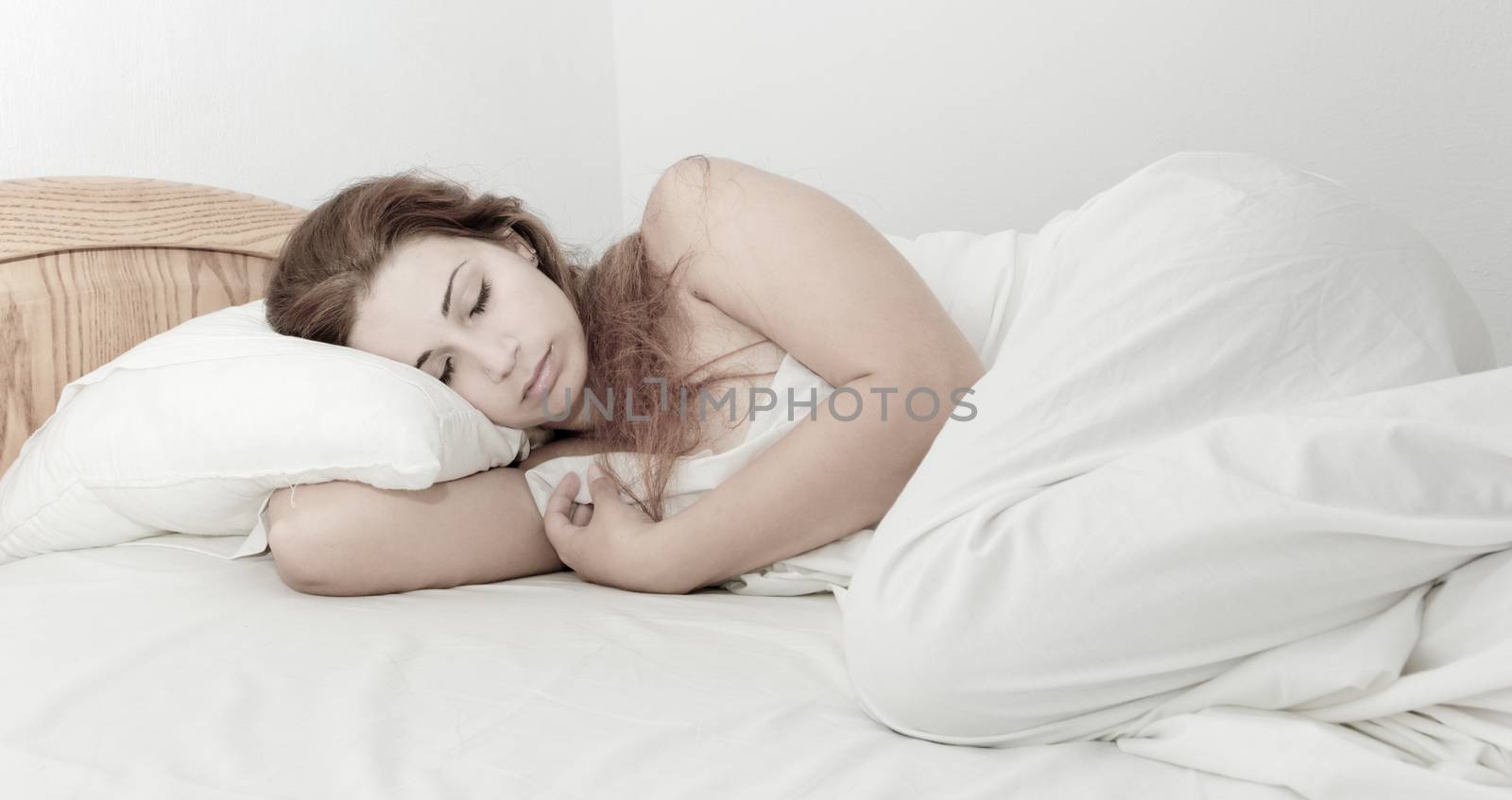 beautiful girl with long brown hair sleeping in the white bed
