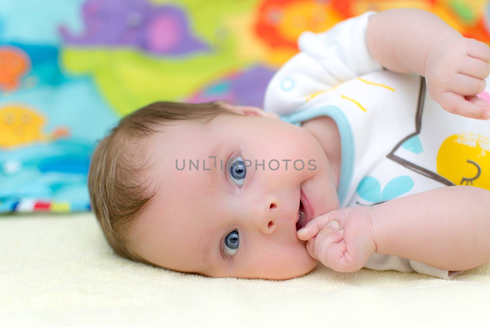 2 months old infant baby girl sucking thumb while lying on bed. Shallow depth of field