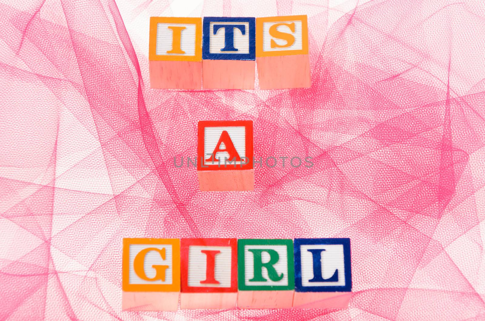 Letter blocks spelling its a girl shot on a pink background