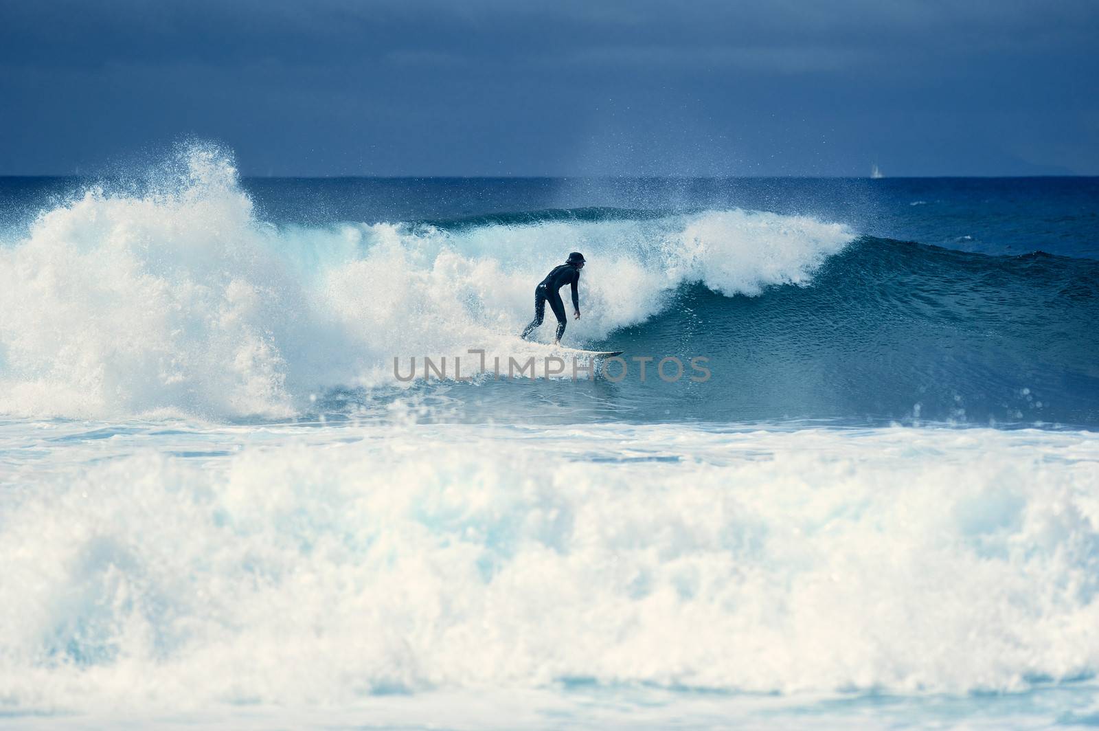Surf-rider on a large blue ocean wave