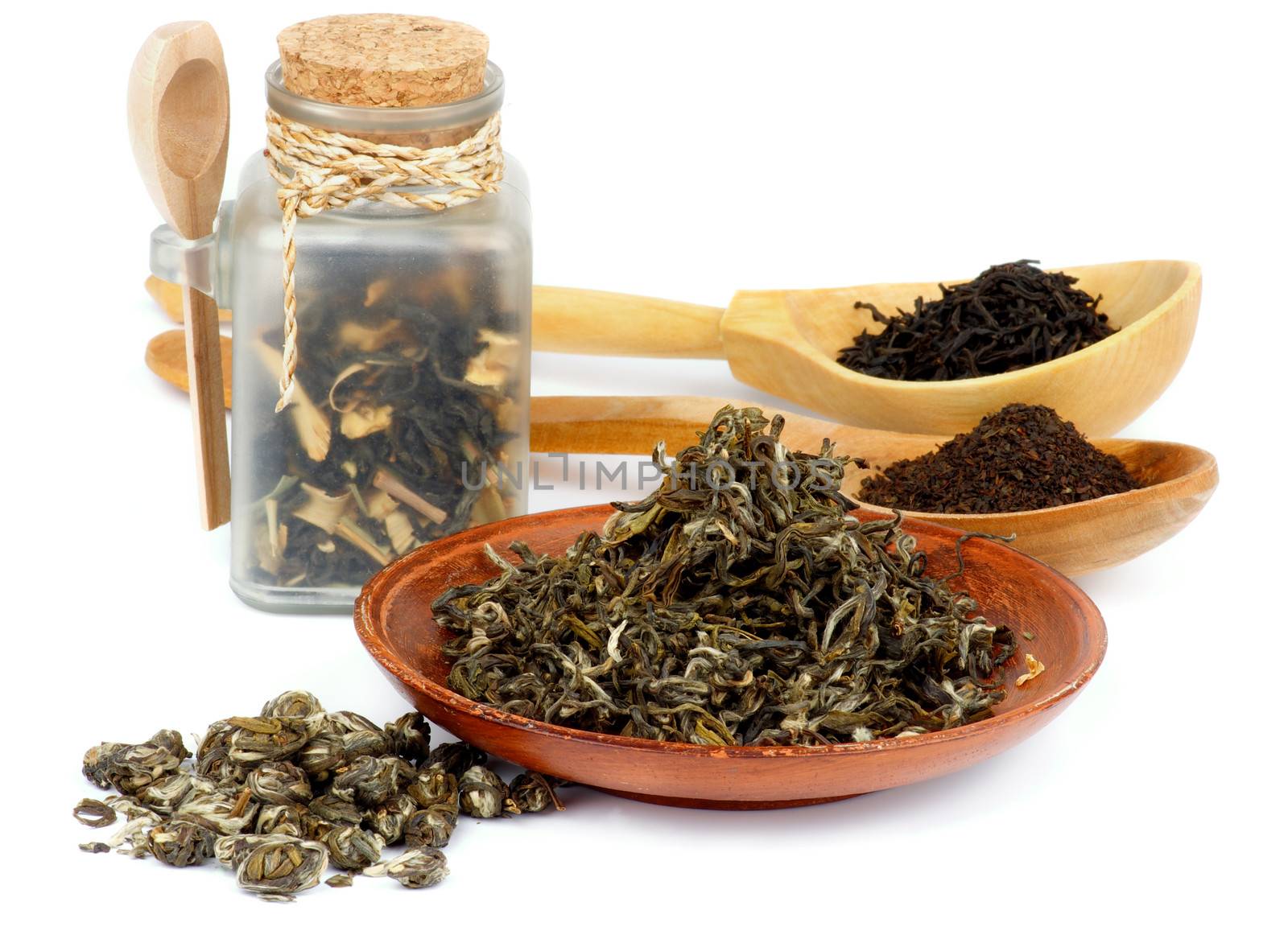 Arrangement of Various Black and Green Tea Leafs in Transparent Container, Wooden Spoons and Plate isolated on white background