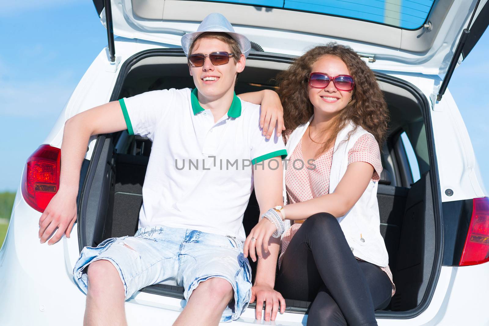 young couple sitting in the open trunk by adam121