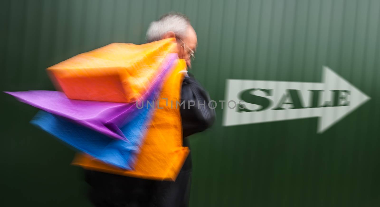 Holiday sales. An elderly man with many shopping bags in his hand. Intentional motion blur