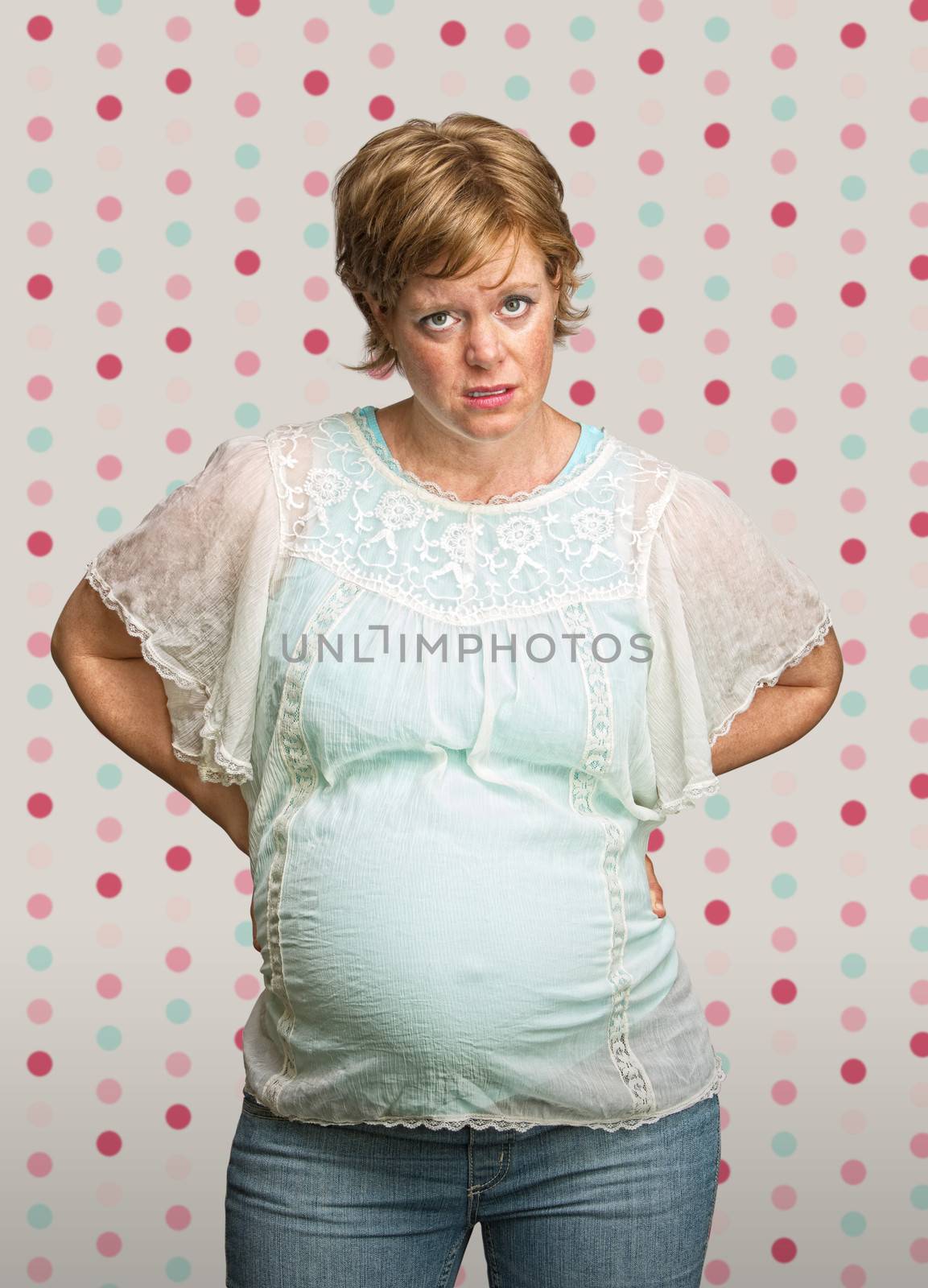 Annoyed pregnant woman on polka dot background