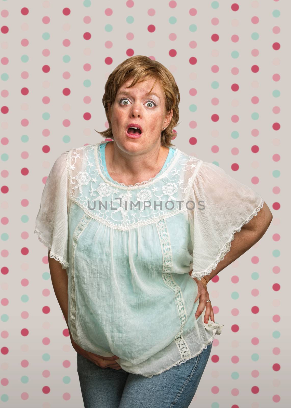 Startled pregnant woman on polka dot background