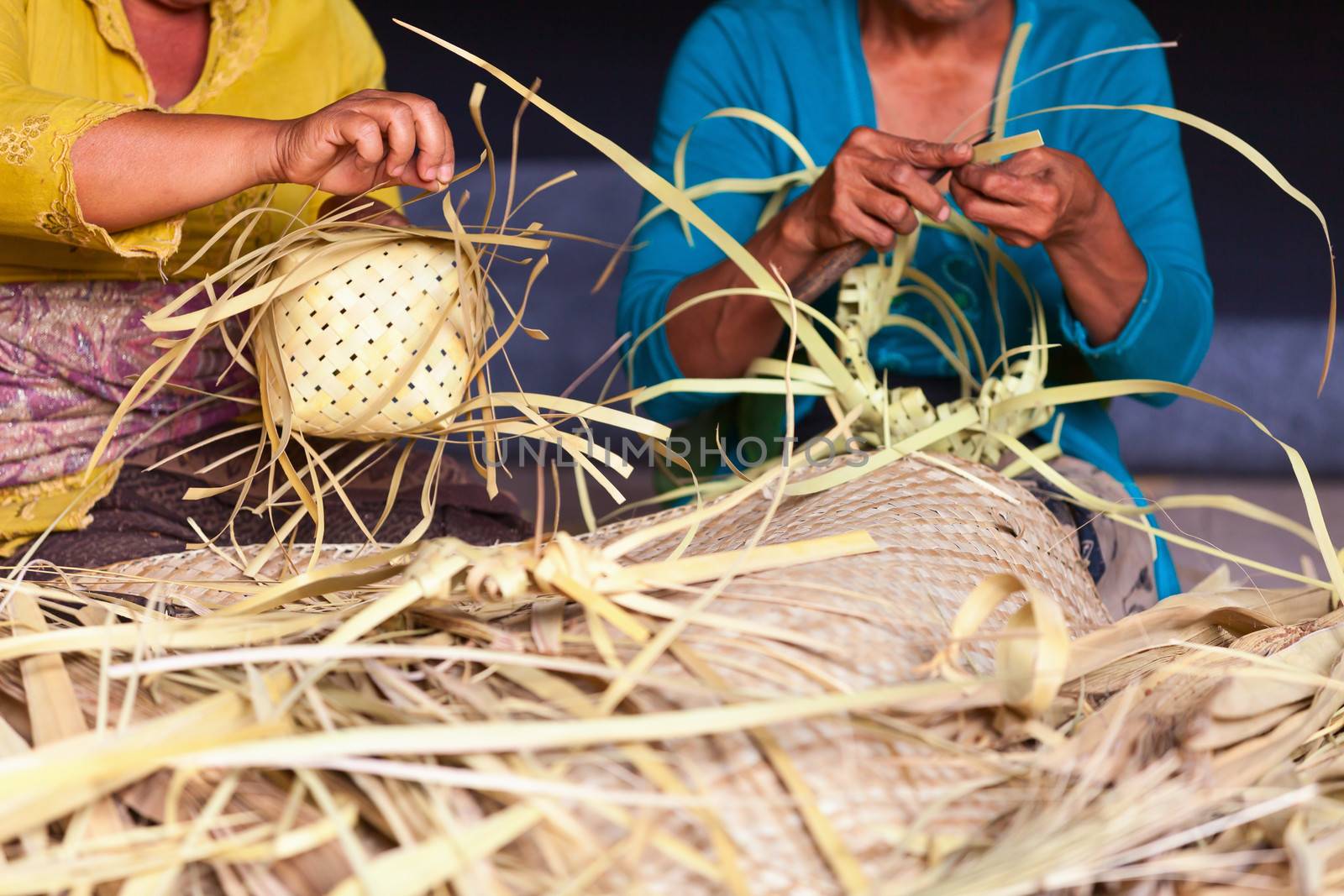 Women make baskets for balinese traditional offerings to gods in a temple, Bali, Indonesia