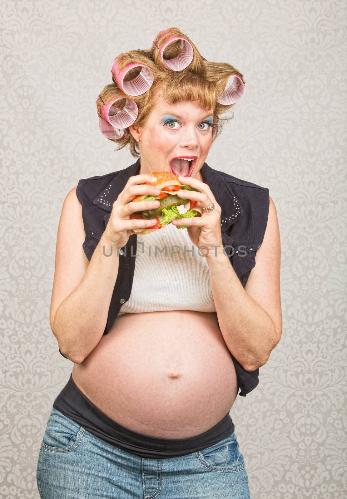 Happy female hillbilly in curlers eating a sandwich