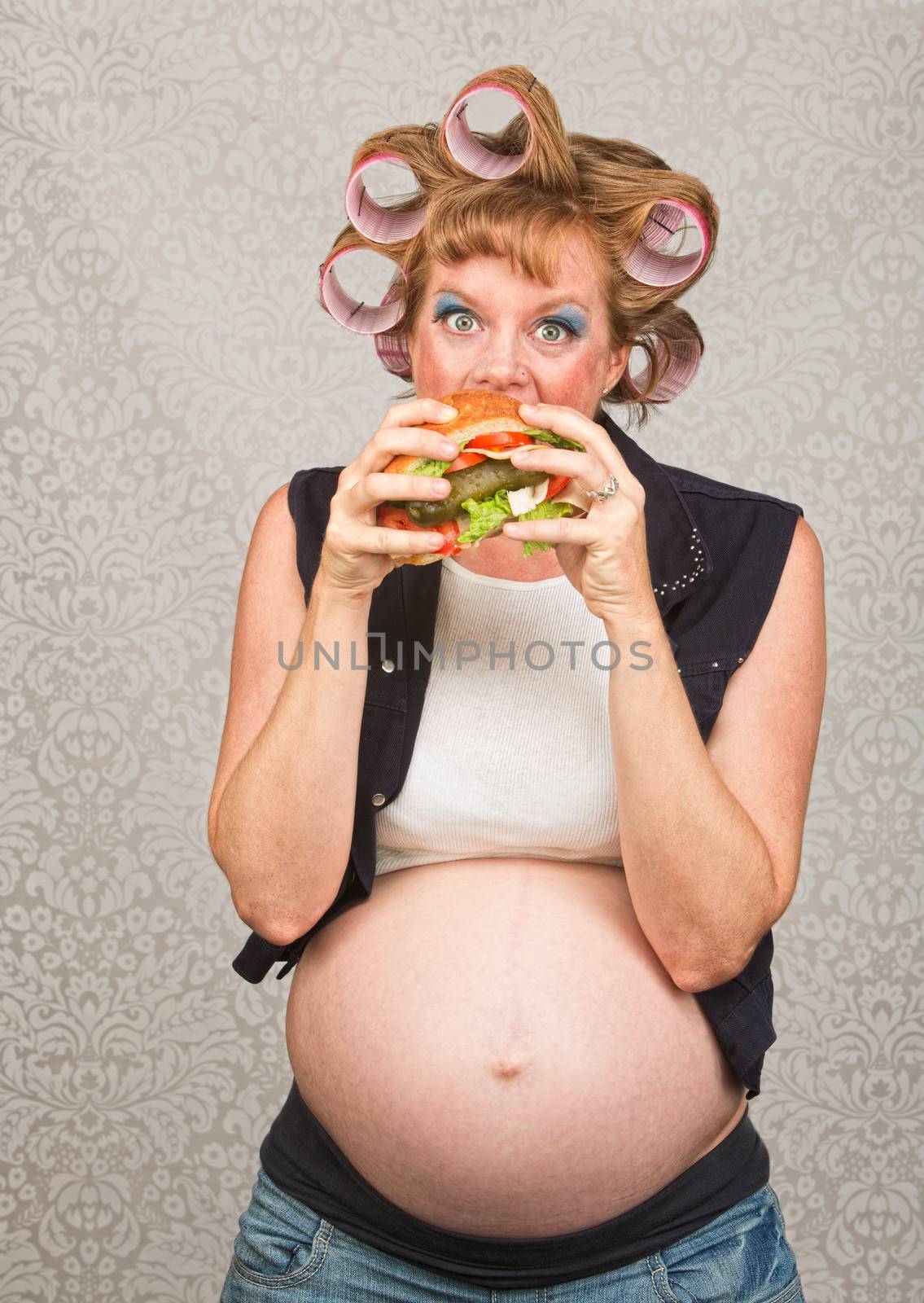 Young pregnant single female eating a sandwich