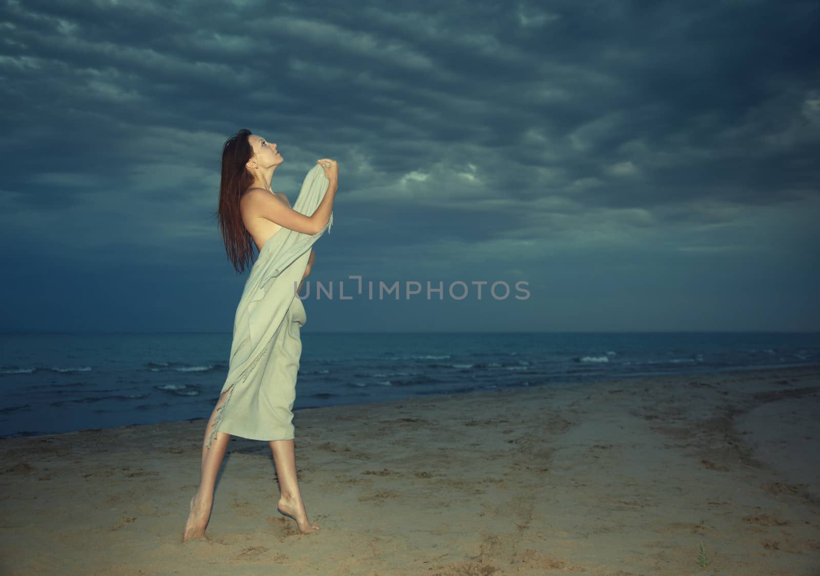 Nifty lady covered by towel standing at the night beach