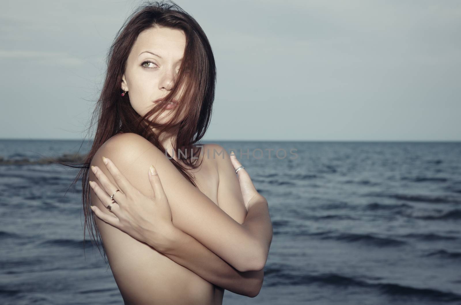 Single lady at the sea with hair blown by the wind. Natural light and colors