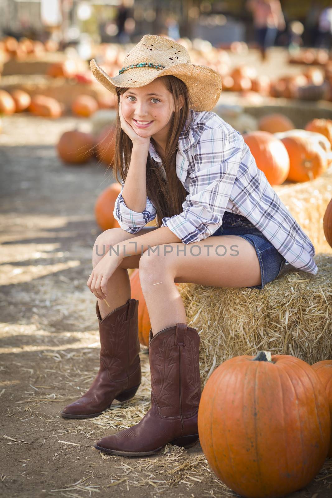 Preteen Girl Wearing Cowboy Hat Portrait at the Pumpkin Patch in a Rustic Setting.