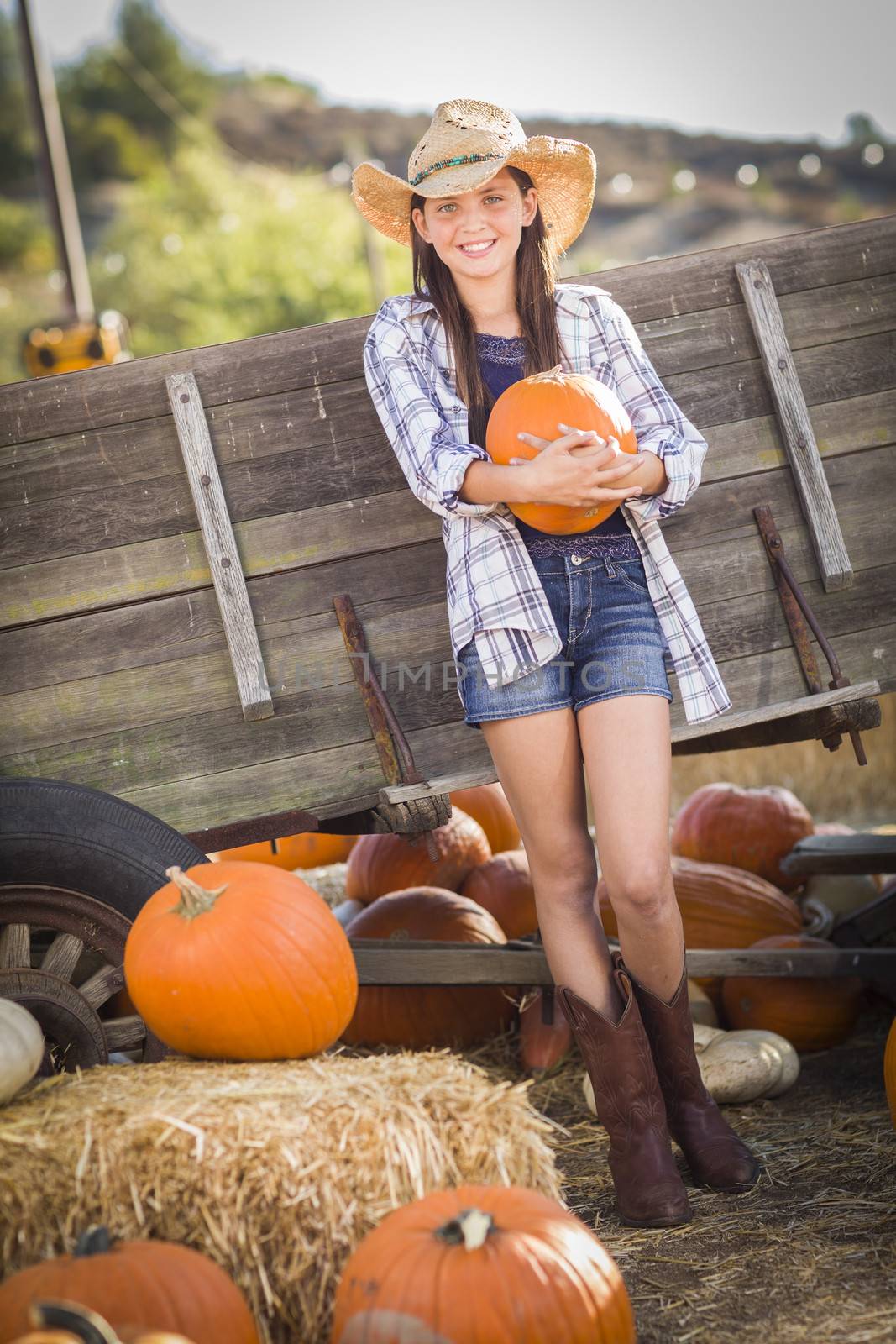 Preteen Girl Wearing Cowboy Hat Portrait at the Pumpkin Patch in a Rustic Setting.