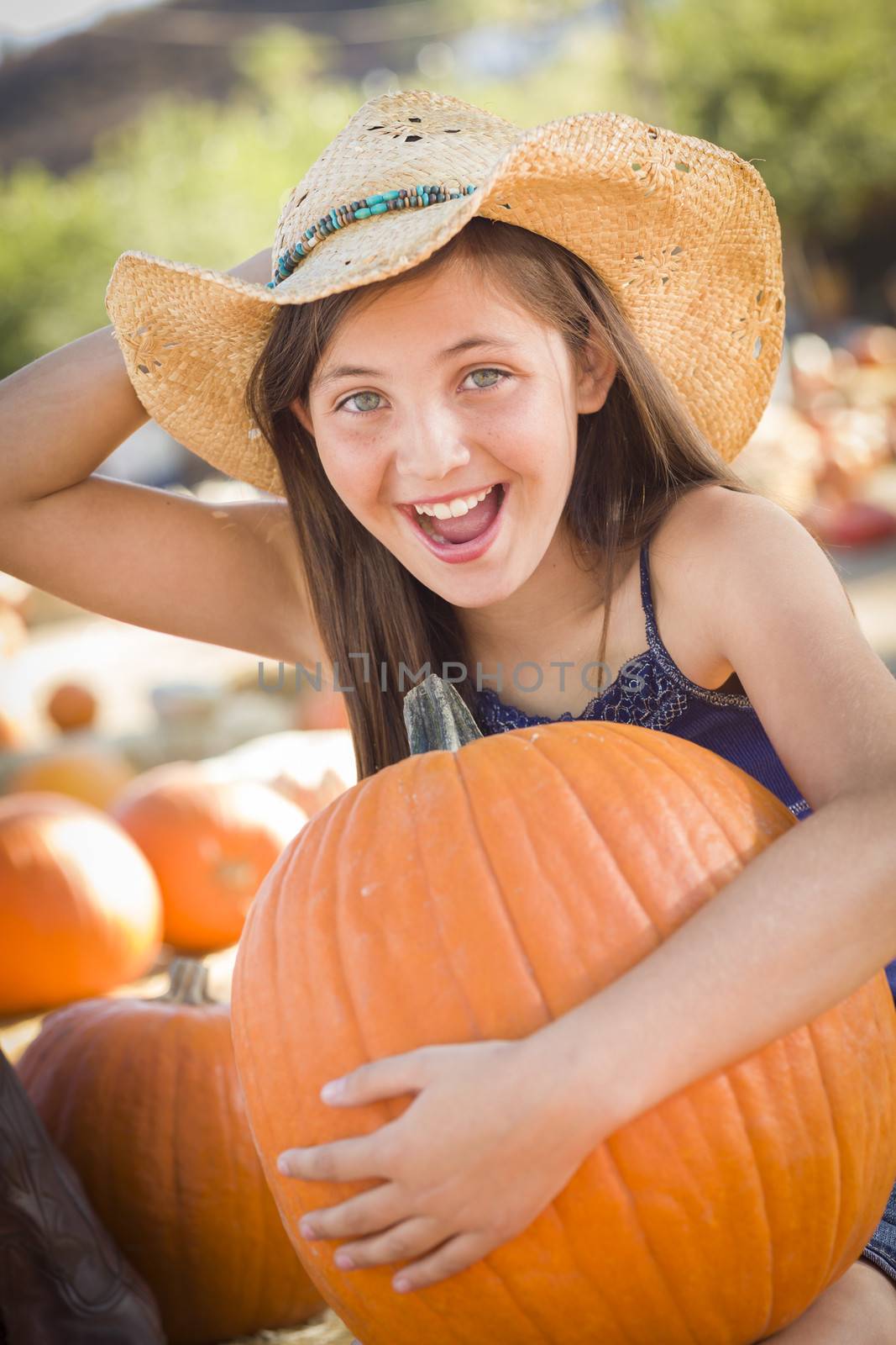 Preteen Girl Holding A Large Pumpkin at the Pumpkin Patch in a Rustic Setting.