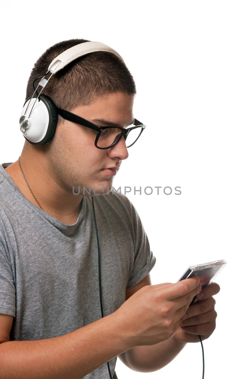 A young man listens to music with a set of head phones while examining the album cd case.