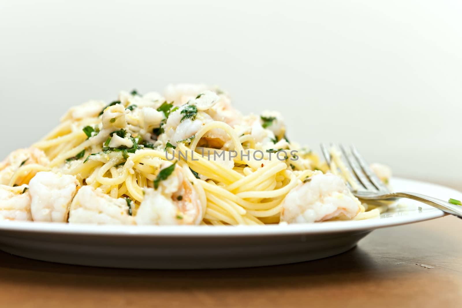 A delicious shrimp scampi pasta dish with calamari parsley garlic and olive oil. Shallow depth of field.