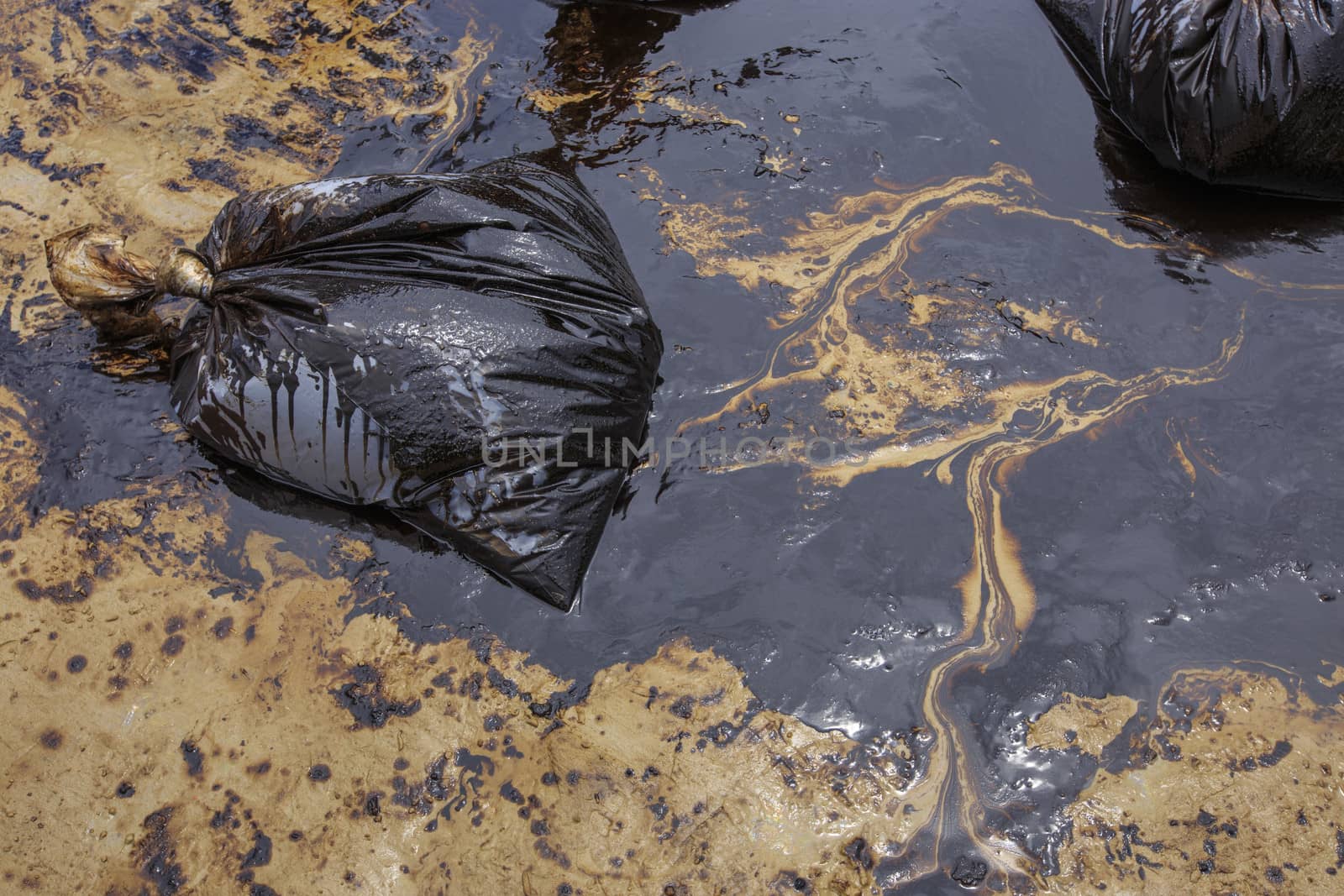 Dirty Sand beach with Plastic bags which contain crude oil from the clean up operation on oil spill accident on Ao Prao Beach at Samet island on July 2013 in Rayong, Thailand.