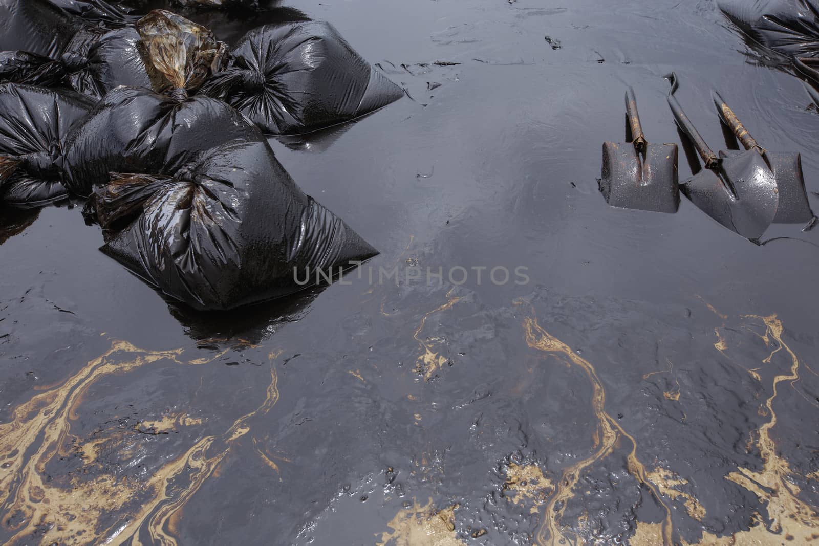 Dirty Sand beach with Spades and Plastic bags which contain crude oil from the clean up operation on oil spill accident on Ao Prao Beach at Samet island on July 2013 in Rayong, Thailand.