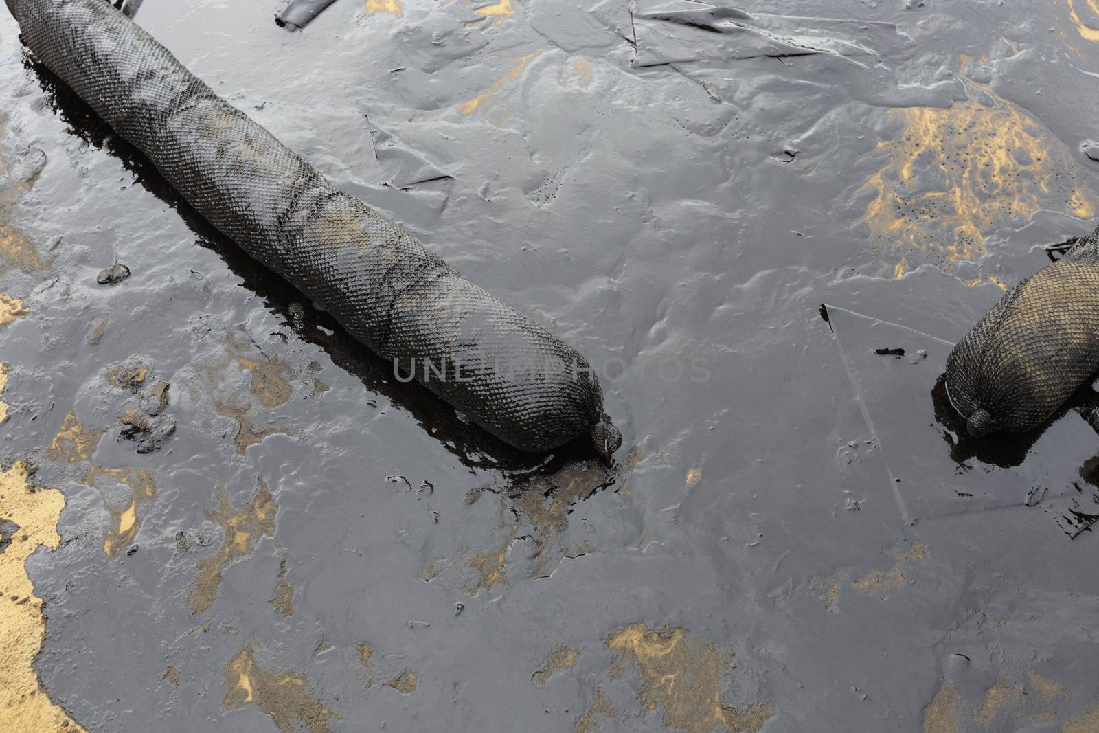 Used Oil Containment Boom on the sand beach that covered with Crude Oil on oil spill accident on Ao Prao Beach at Samet island on July 2013 in Rayong province, Thailand.