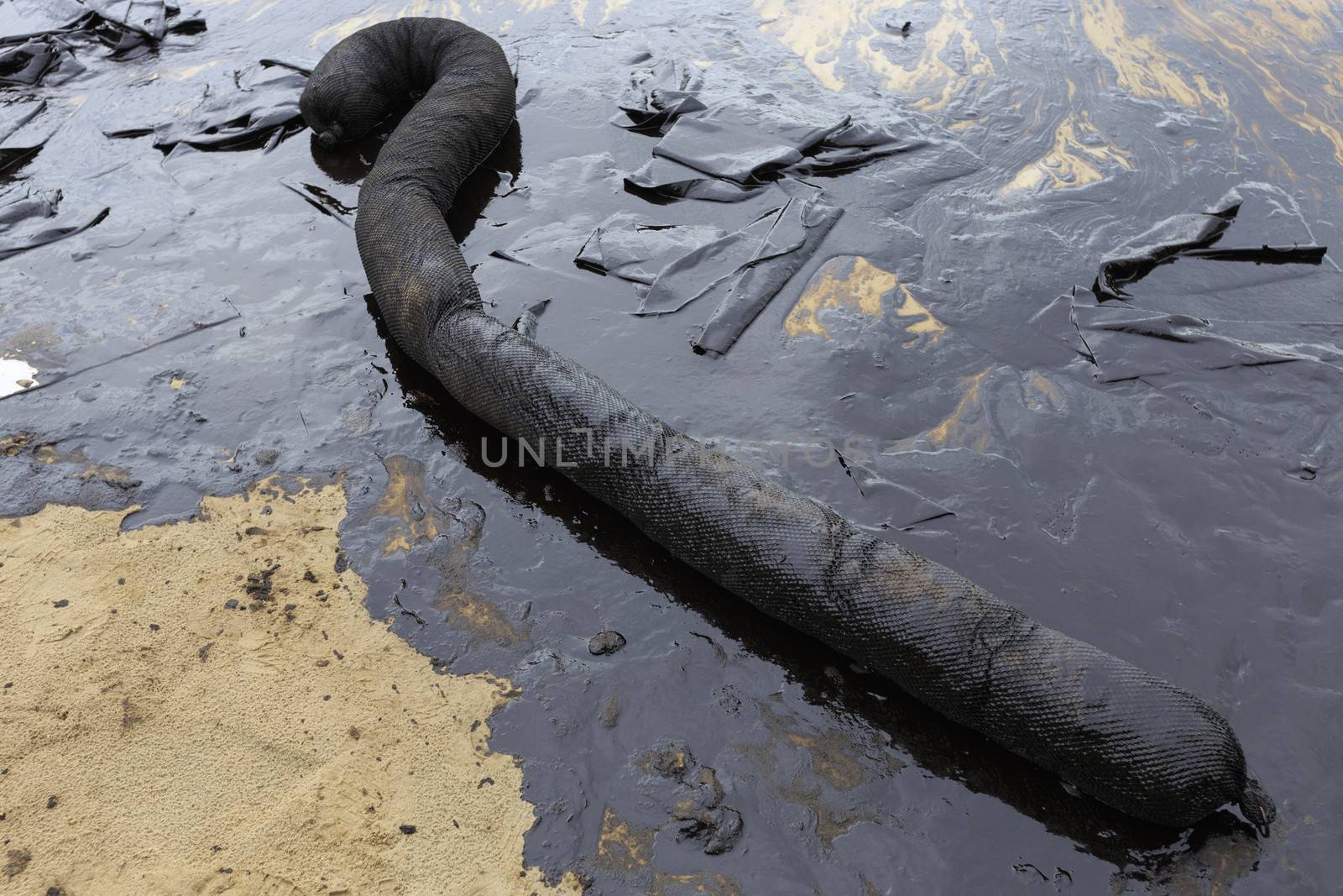 Used Oil Containment Boom on the sand beach that covered with Crude Oil on oil spill accident on Ao Prao Beach at Samet island on July 2013 in Rayong province, Thailand.