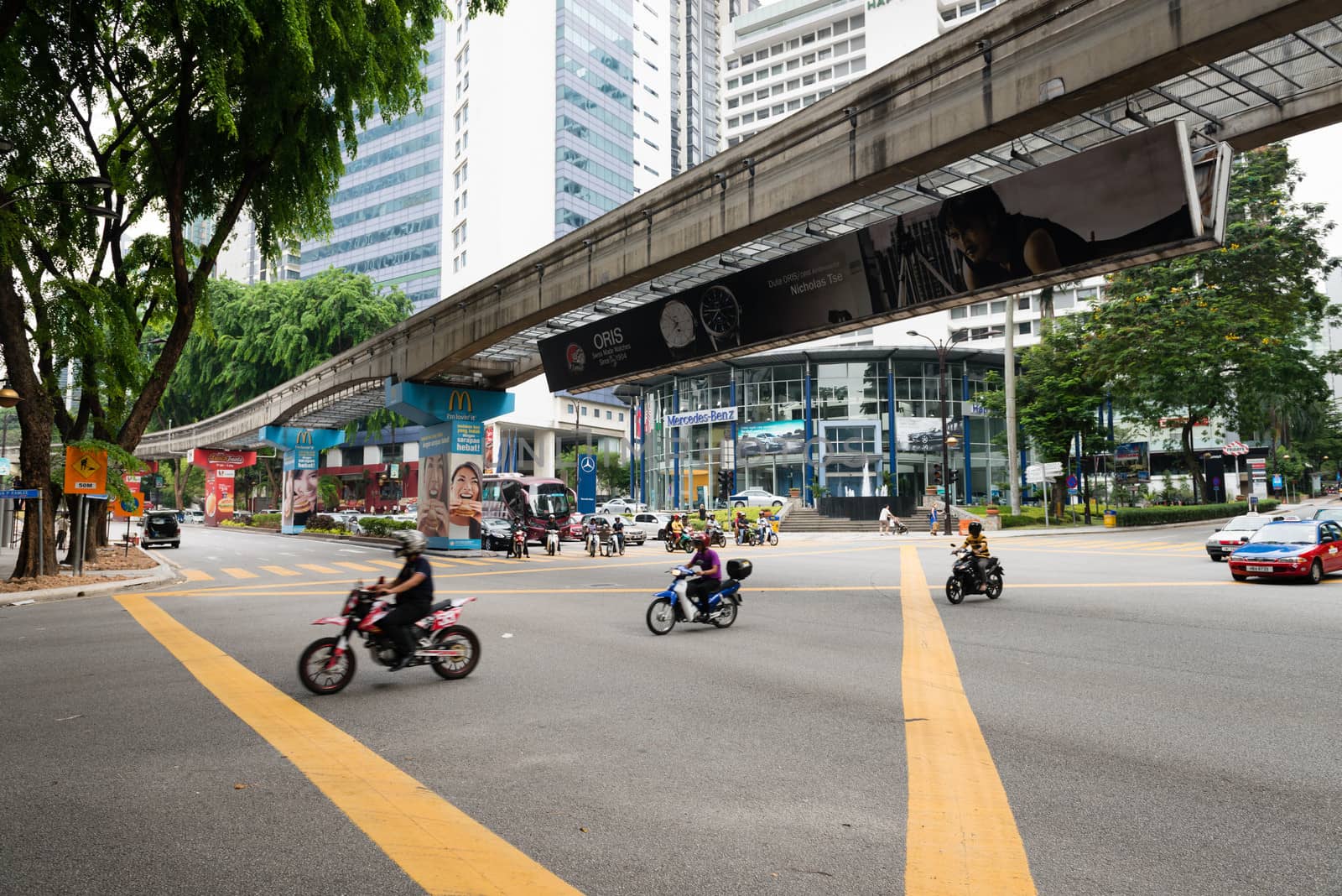 KUALA LUMPUR - JUN 15: City street with motorbikes and  monorail way under road on Jun 15, 2013 in Kuala Lumpur, Malaysia. Kuala Lumpur is served by three separate rail systems with underground, elevated or at-grade lines.