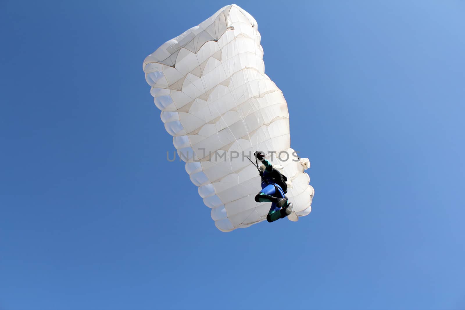 parachutist with white parachute on blue sky by goce