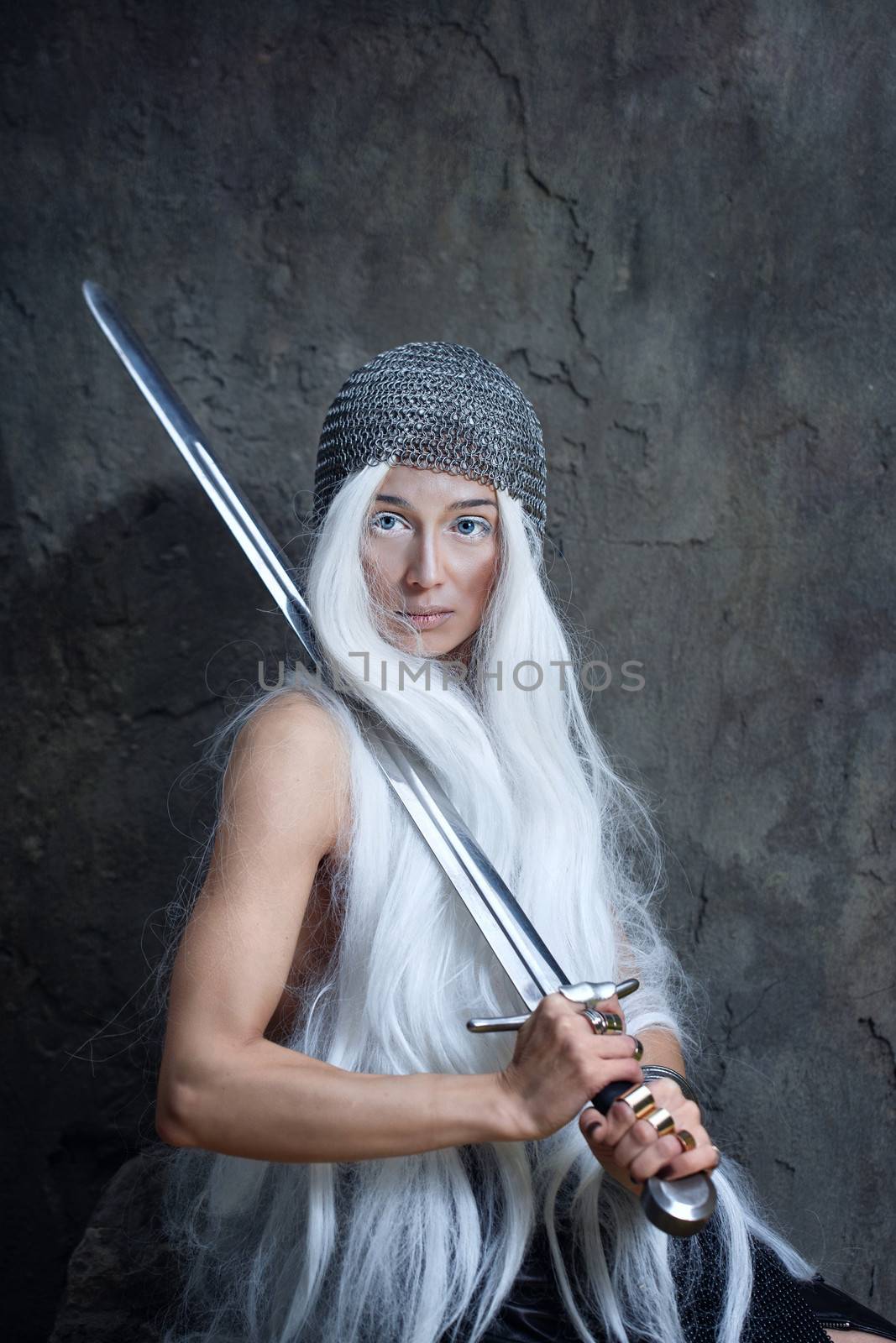 Androgyny girl in armor with a sword and looking at the camera