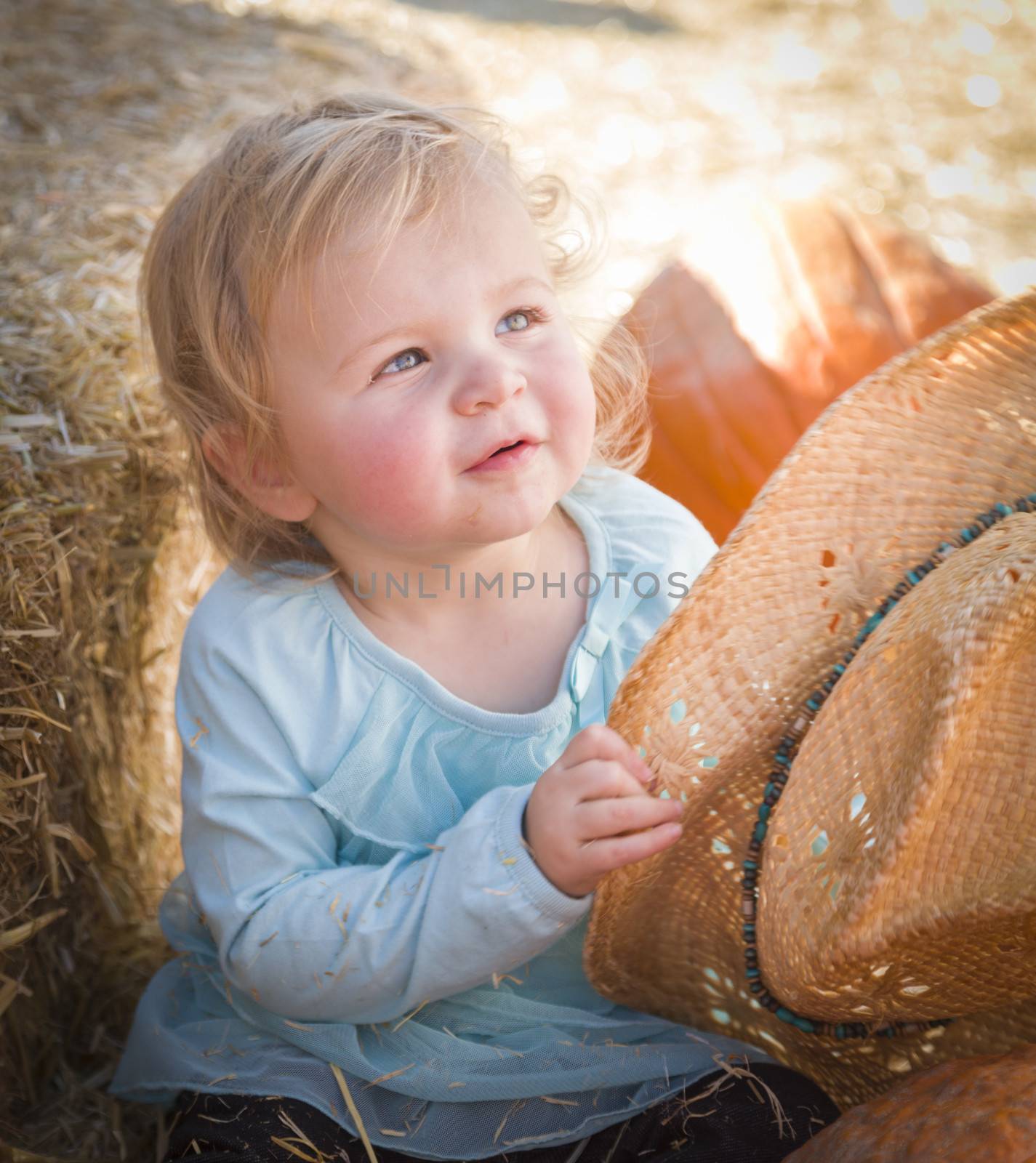 Adorable Baby Girl with Cowboy Hat in a Country Rustic Setting at the Pumpkin Patch.