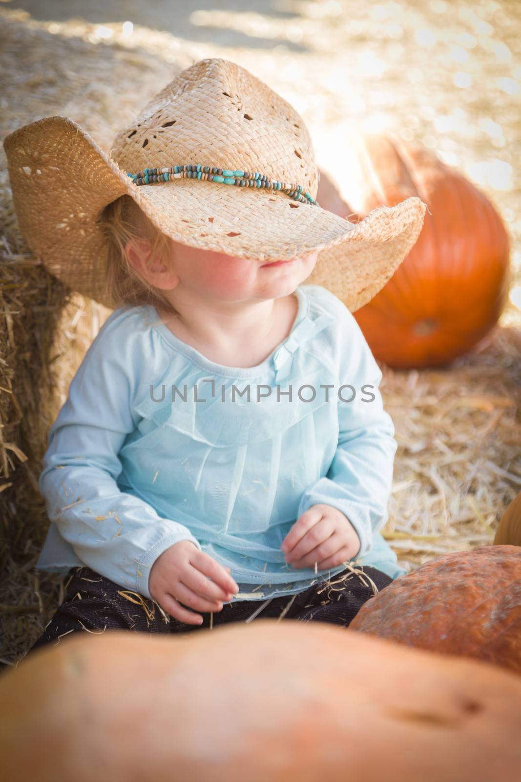 Adorable Baby Girl with Cowboy Hat in a Country Rustic Setting at the Pumpkin Patch.