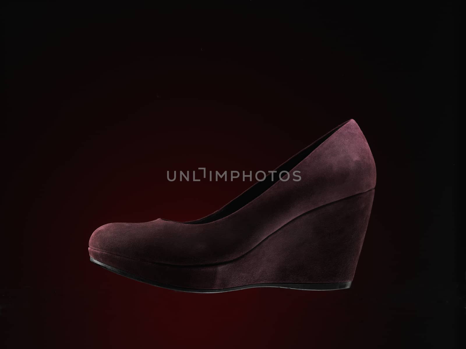 red suede shoes over dark red background