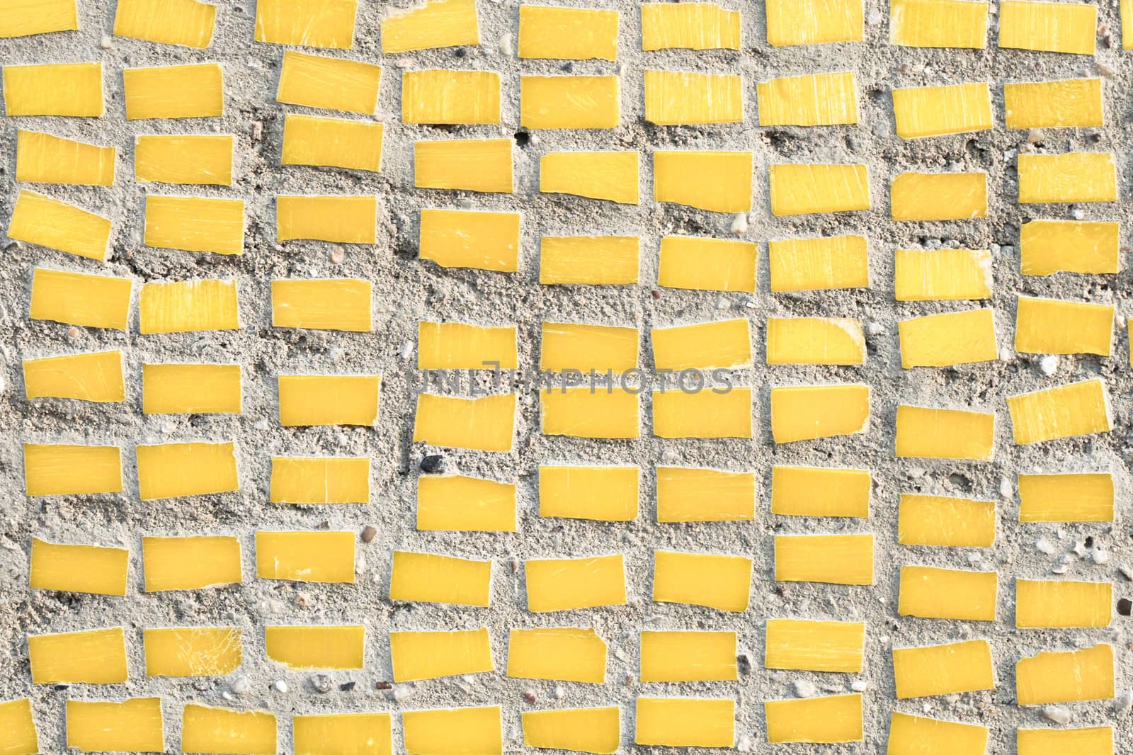 small yellow tiles on a stone surface as a background