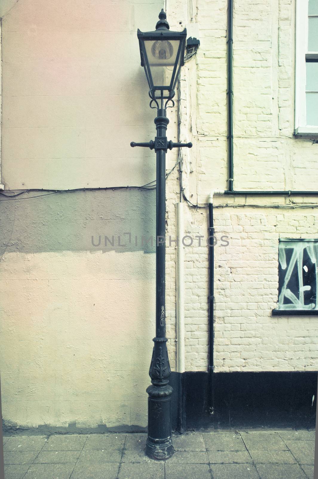 Vintage lamp post against an urban wall