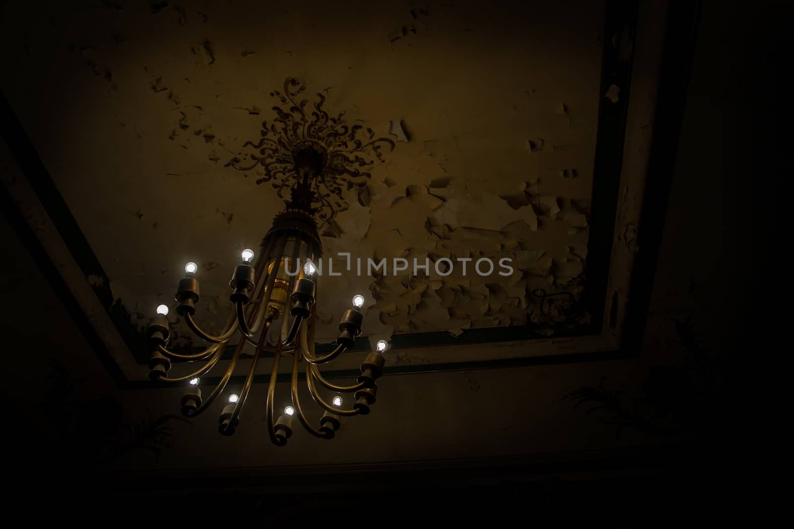Interior scene of a chandelier in a grungy and dark concrete wasted room.