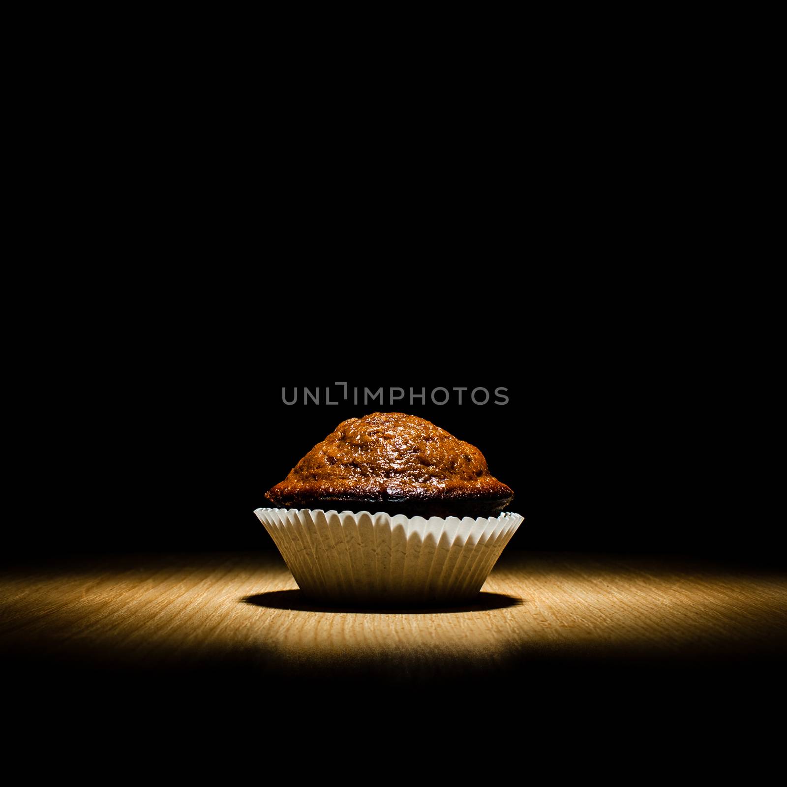 Chocolate muffin, freshbaked from the oven, on a wooden table.
